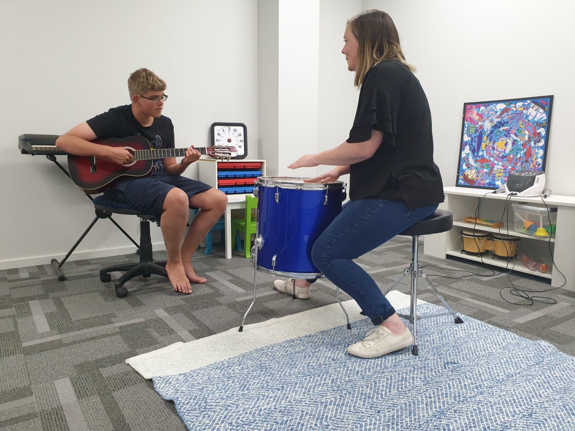 Music teacher and participant play drums and guitar together