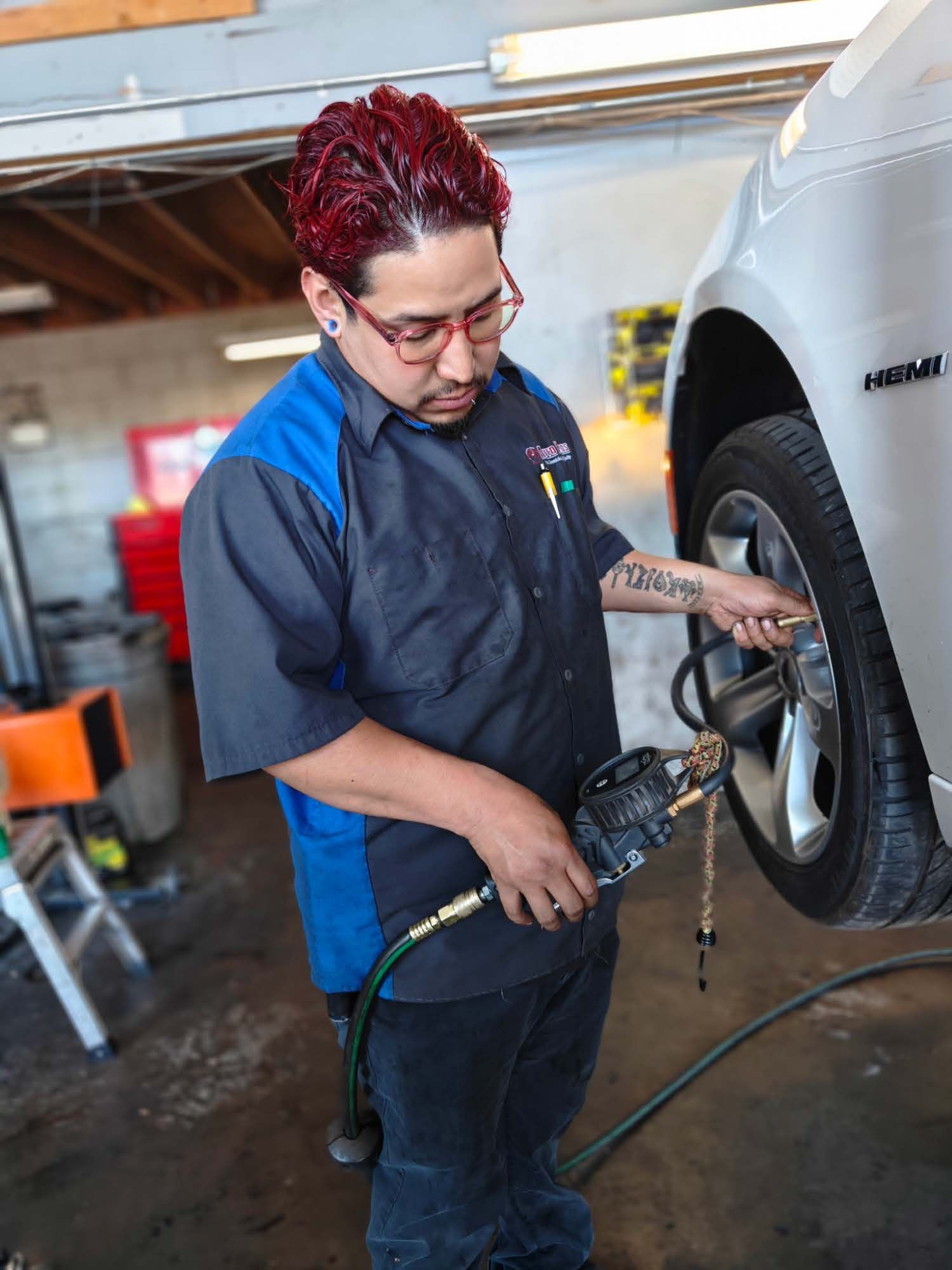 Mechanic using an air impact wrench to work on a car wheel in a garage | Auto Pros