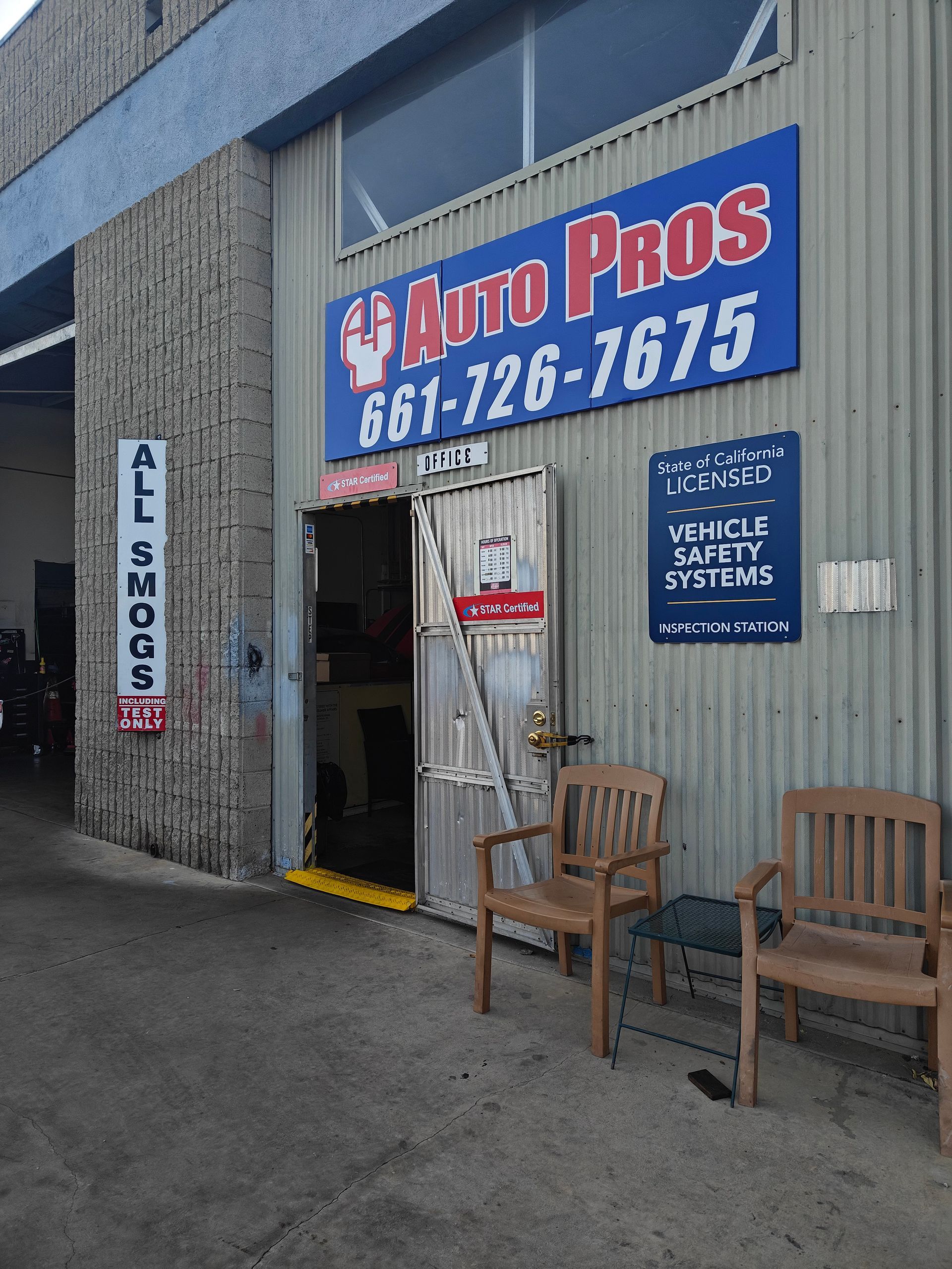 Auto Pros auto repair shop entrance with blue sign, doorway, and chairs outside | Auto Pros