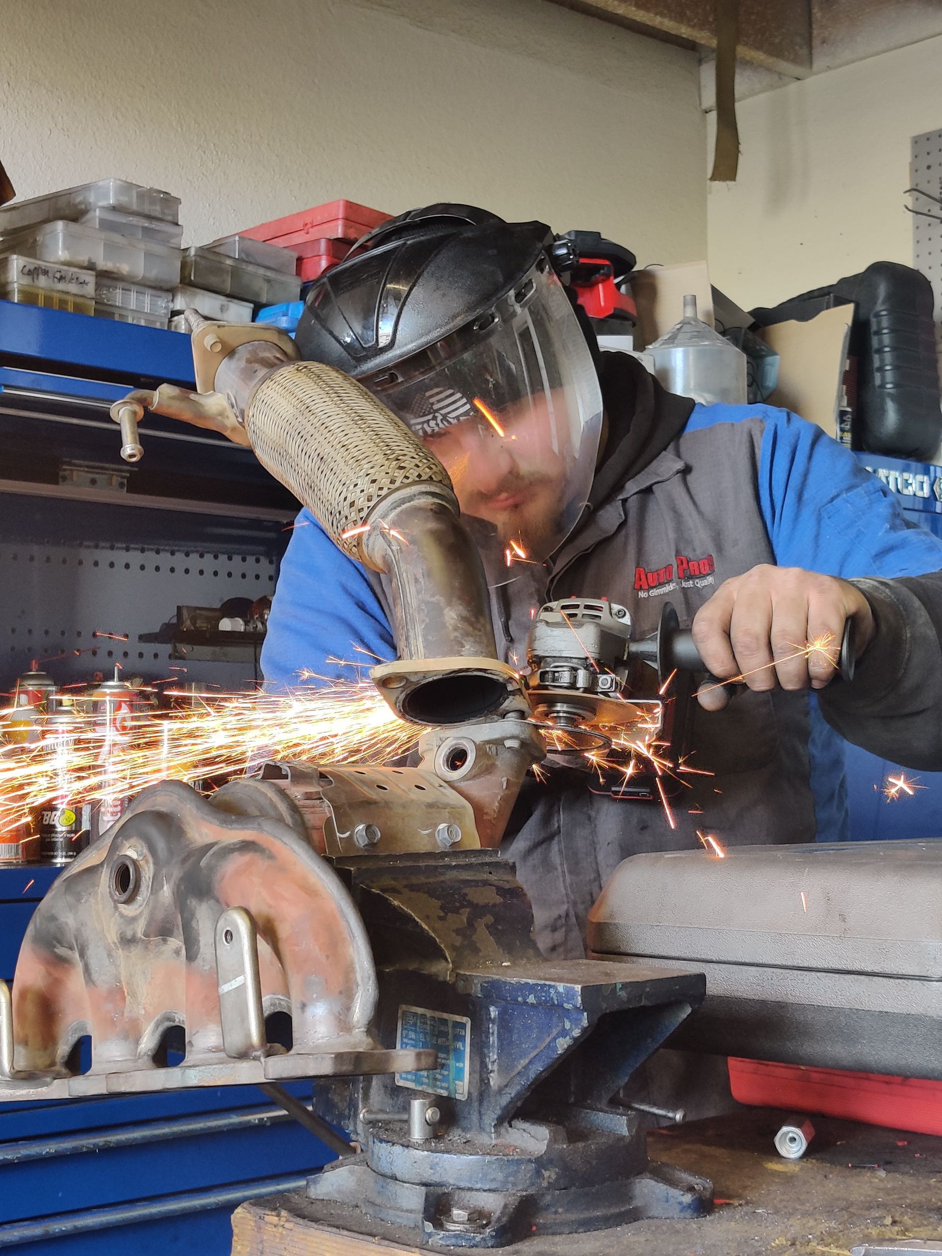 Person using a grinder on a metal part, with sparks flying in a workshop. | Auto Pros