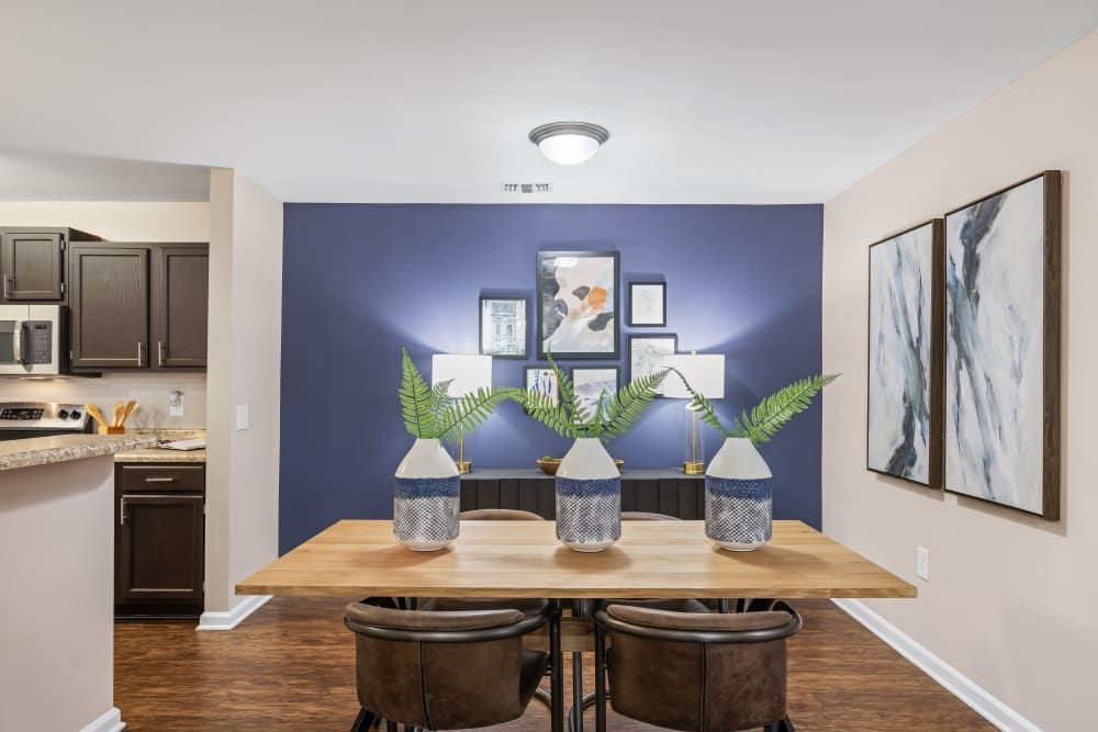 a dining room with a wooden table and chairs and a blue wall at Marquis on Cary Parkway in Morrisville, NC.