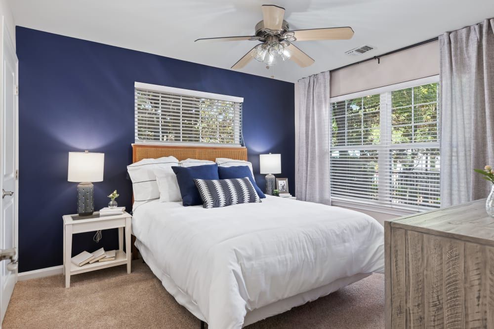 a bedroom with a bed, nightstand, dresser, and ceiling fan at Marquis on Cary Parkway in Morrisville, NC.