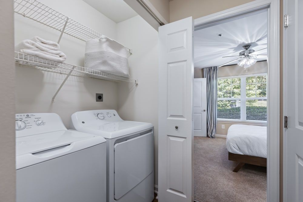 a laundry room with a washer and dryer next to a bedroom at Marquis on Cary Parkway in Morrisville, NC.