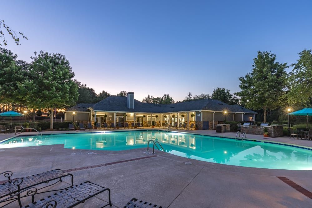 a large swimming pool is lit up at night in front of a house at Marquis on Cary Parkway in Morrisville, NC.