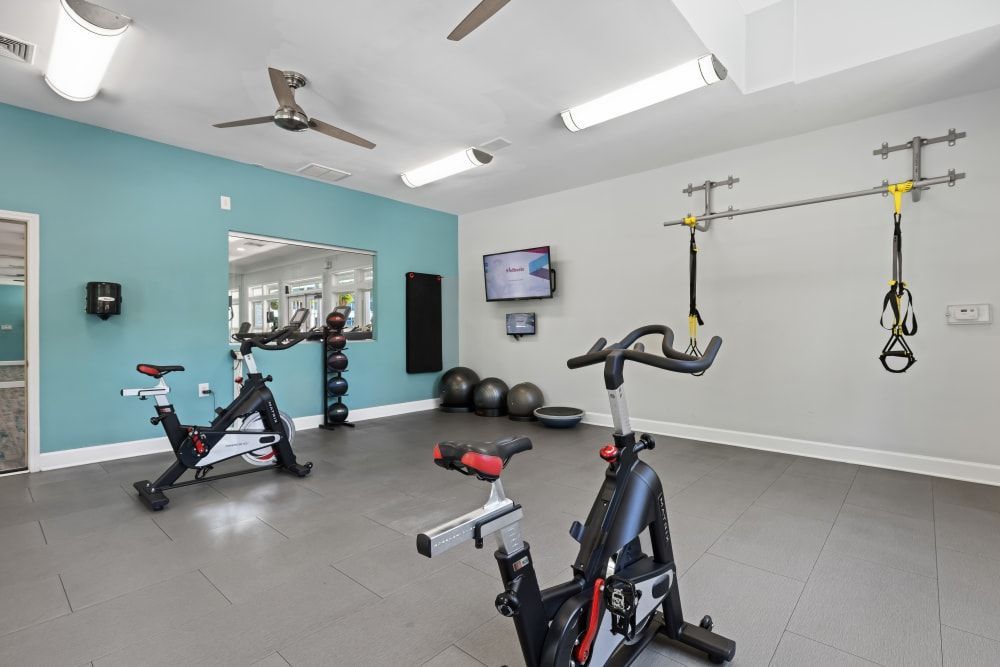 a gym with a lot of exercise equipment and a ceiling fan at Marquis on Cary Parkway in Morrisville, NC.