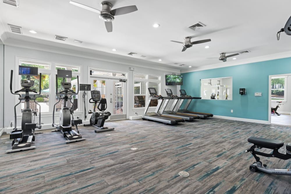 a large gym with a lot of equipment and a ceiling fan at Marquis on Cary Parkway in Morrisville, NC