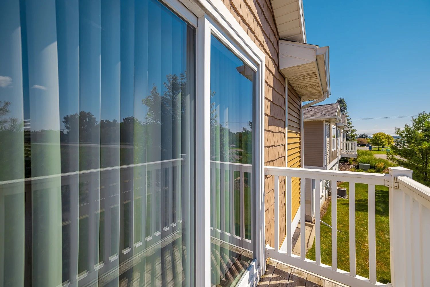 A balcony with a sliding glass door and a white railing.