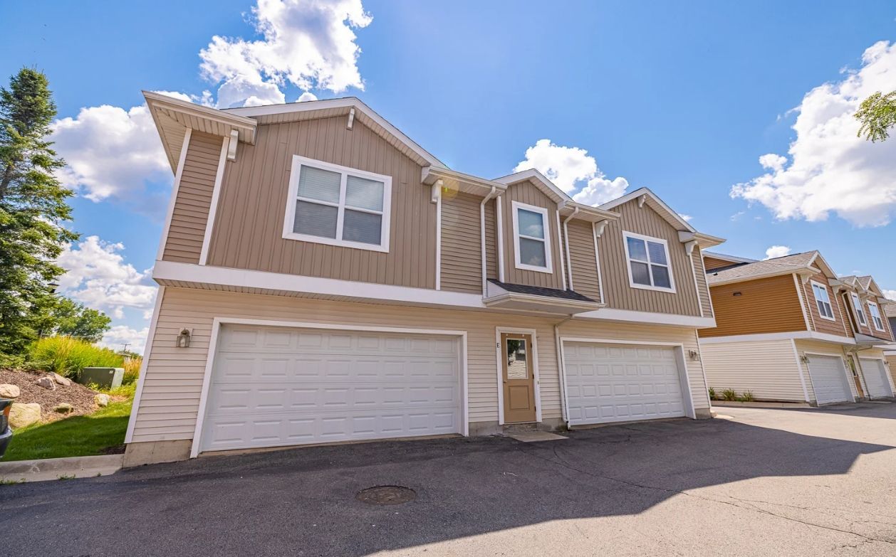 A house with three garage doors and a blue sky in the background