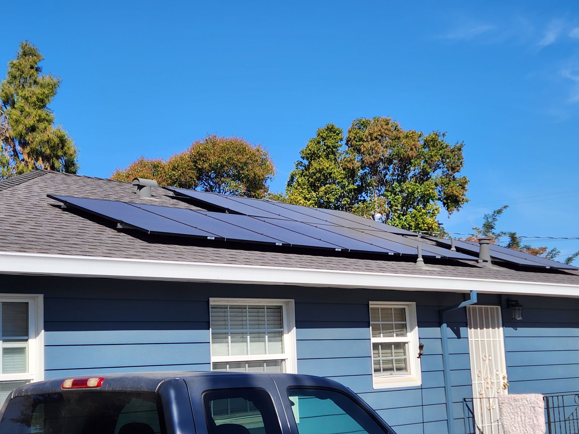 A truck is parked in front of a house with solar panels on the roof.