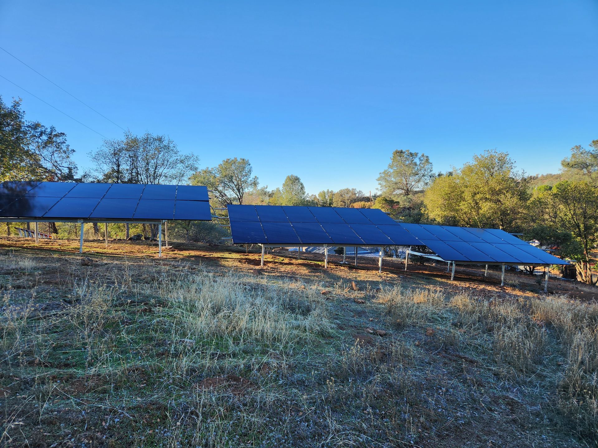 A row of solar panels sitting on top of a grassy hill.