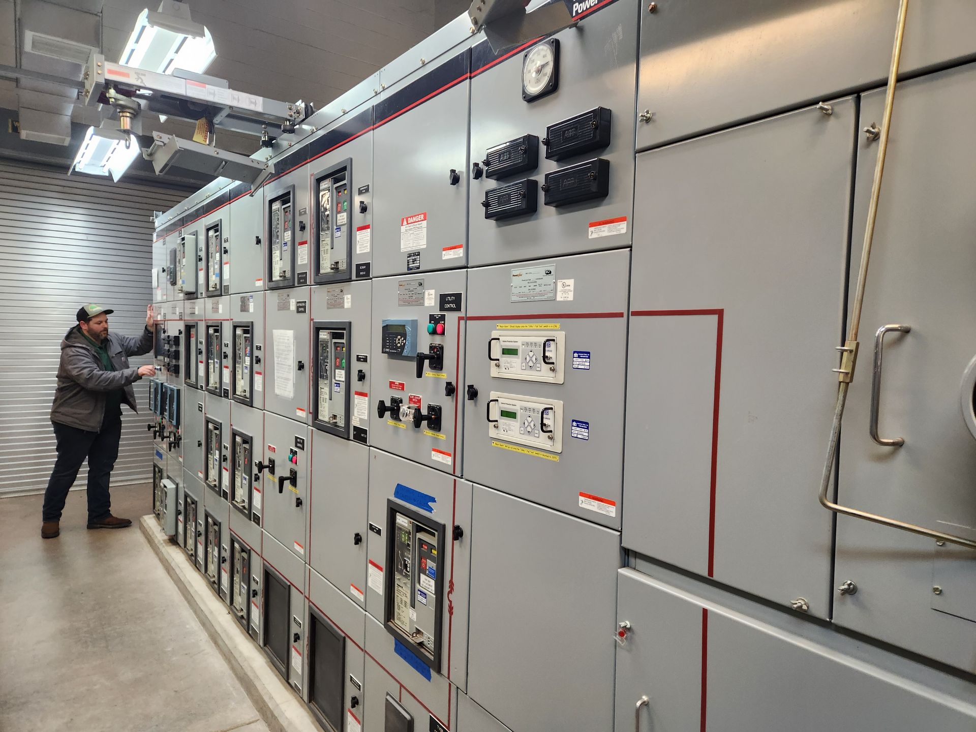 A man is working on a large electrical panel in a room.