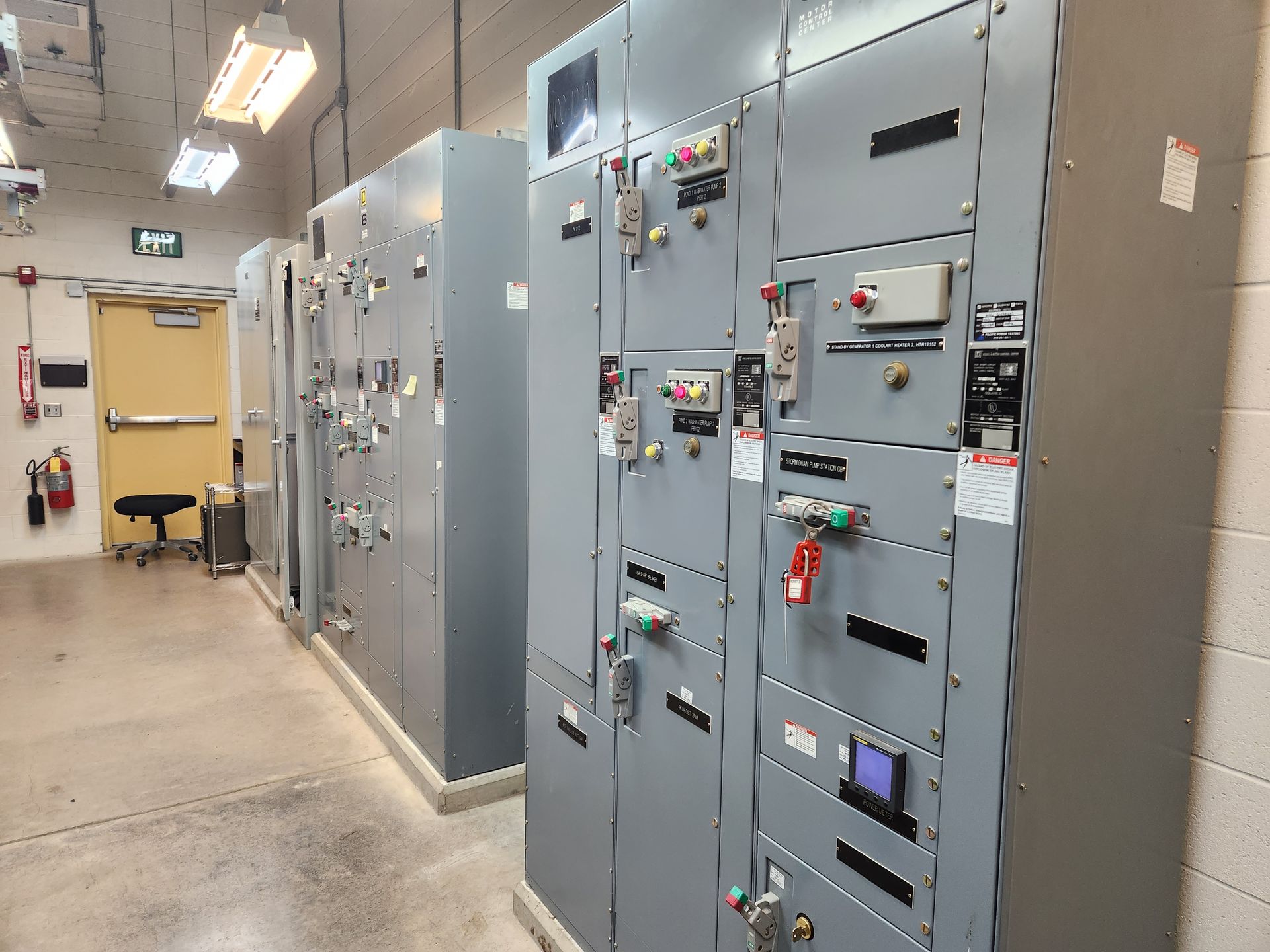 A row of electrical boxes in a room with a yellow door.