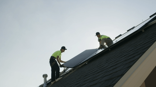 Two men are working on the roof of a house