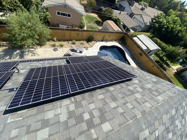 A roof with solar panels on it and a pool in the background