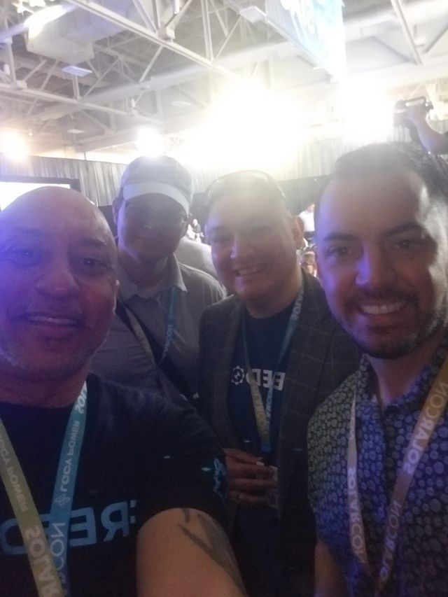 A group of men are posing for a picture with one wearing a shirt that says 