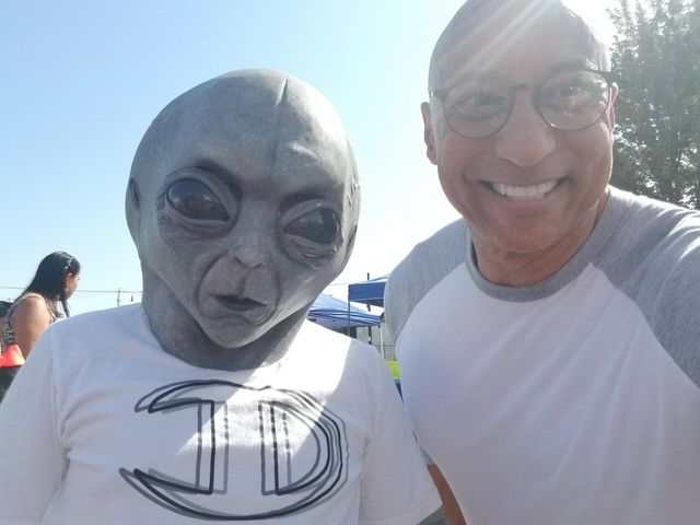 A man wearing a td shirt poses with an alien