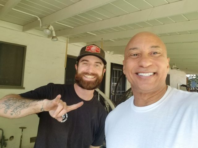 Two men are posing for a picture and one is pointing at the camera