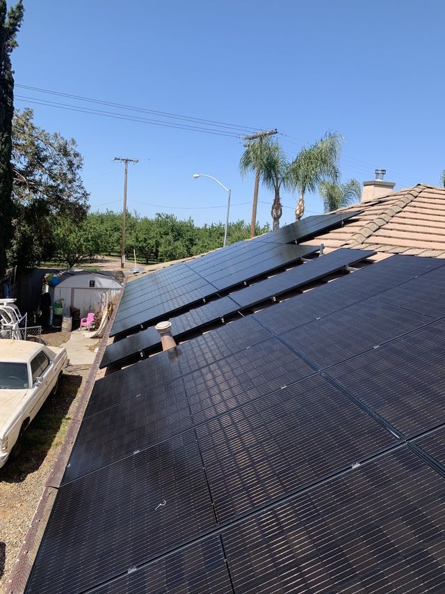 There are many solar panels on the roof of a house.