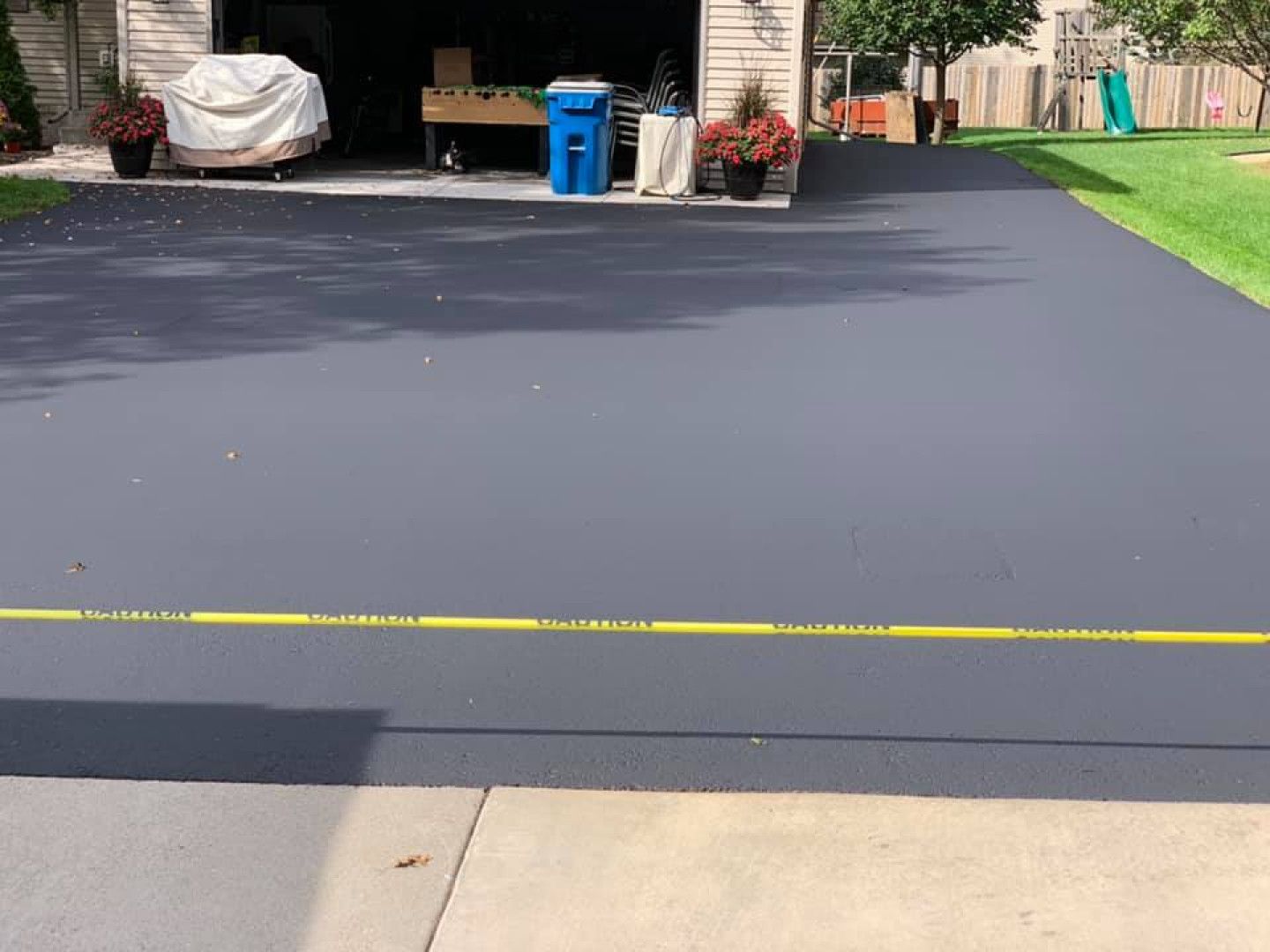 A gray driveway with a yellow line on the side of it leading to a garage.