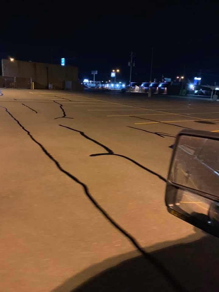 A car is parked in a parking lot at night.