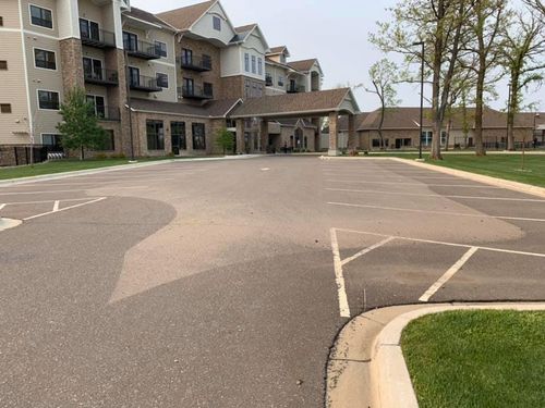 A parking lot in front of a large apartment building.