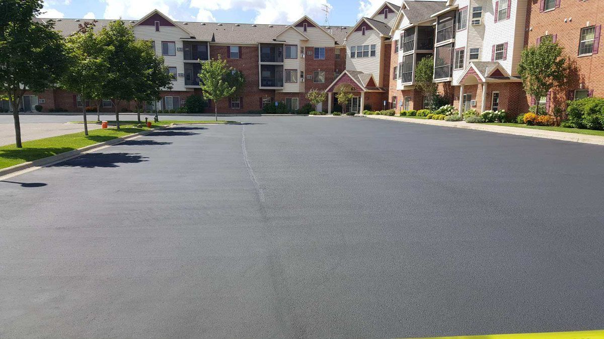 A parking lot in front of a large apartment building.