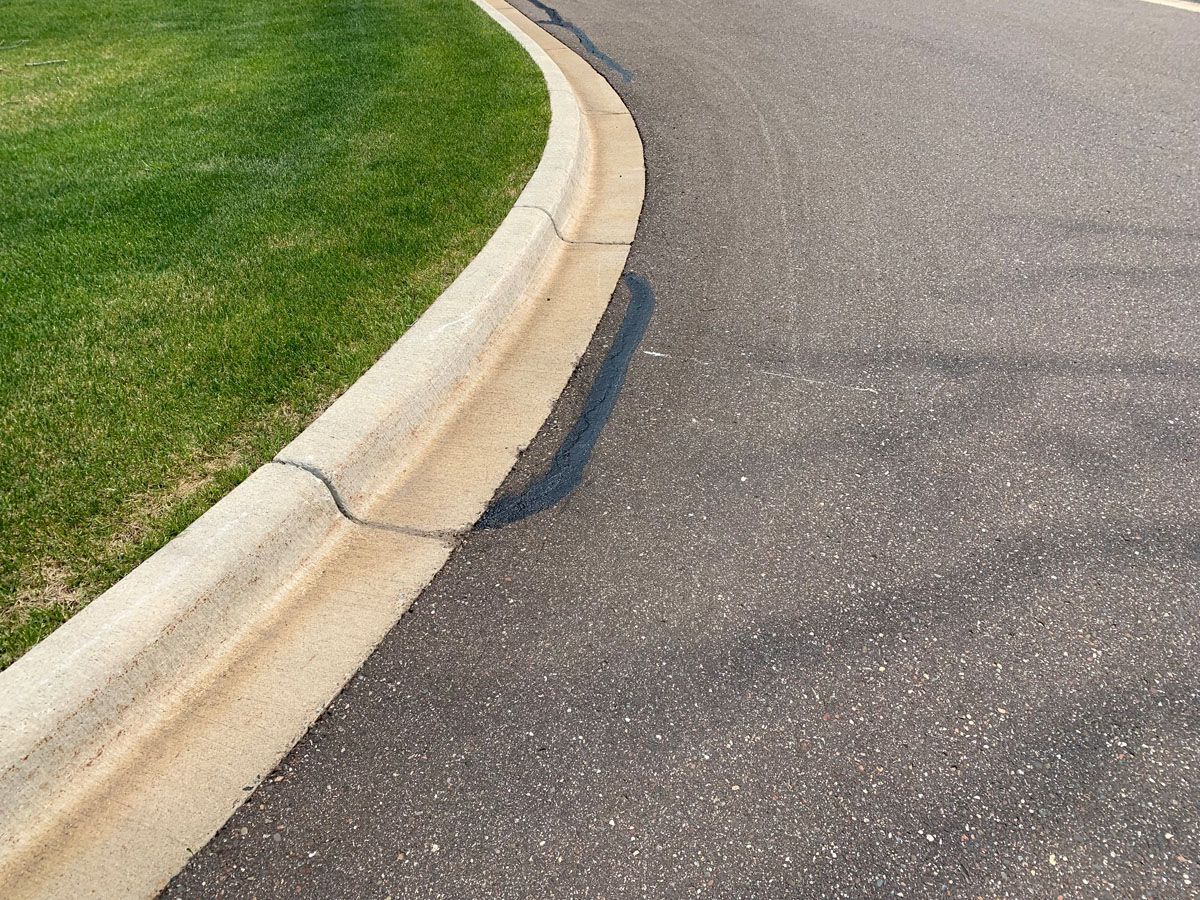 A curb on the side of a road next to a grassy area.