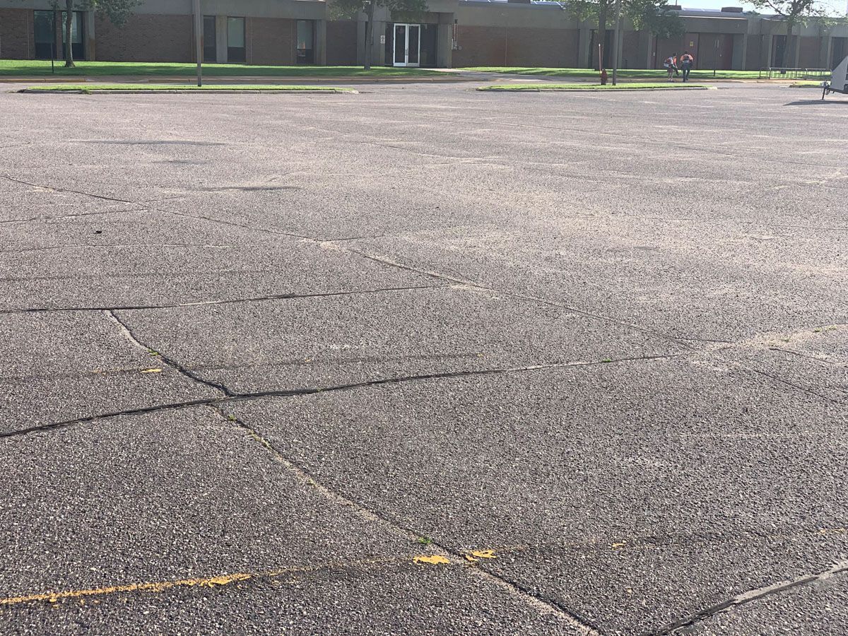 A large empty parking lot with a building in the background.