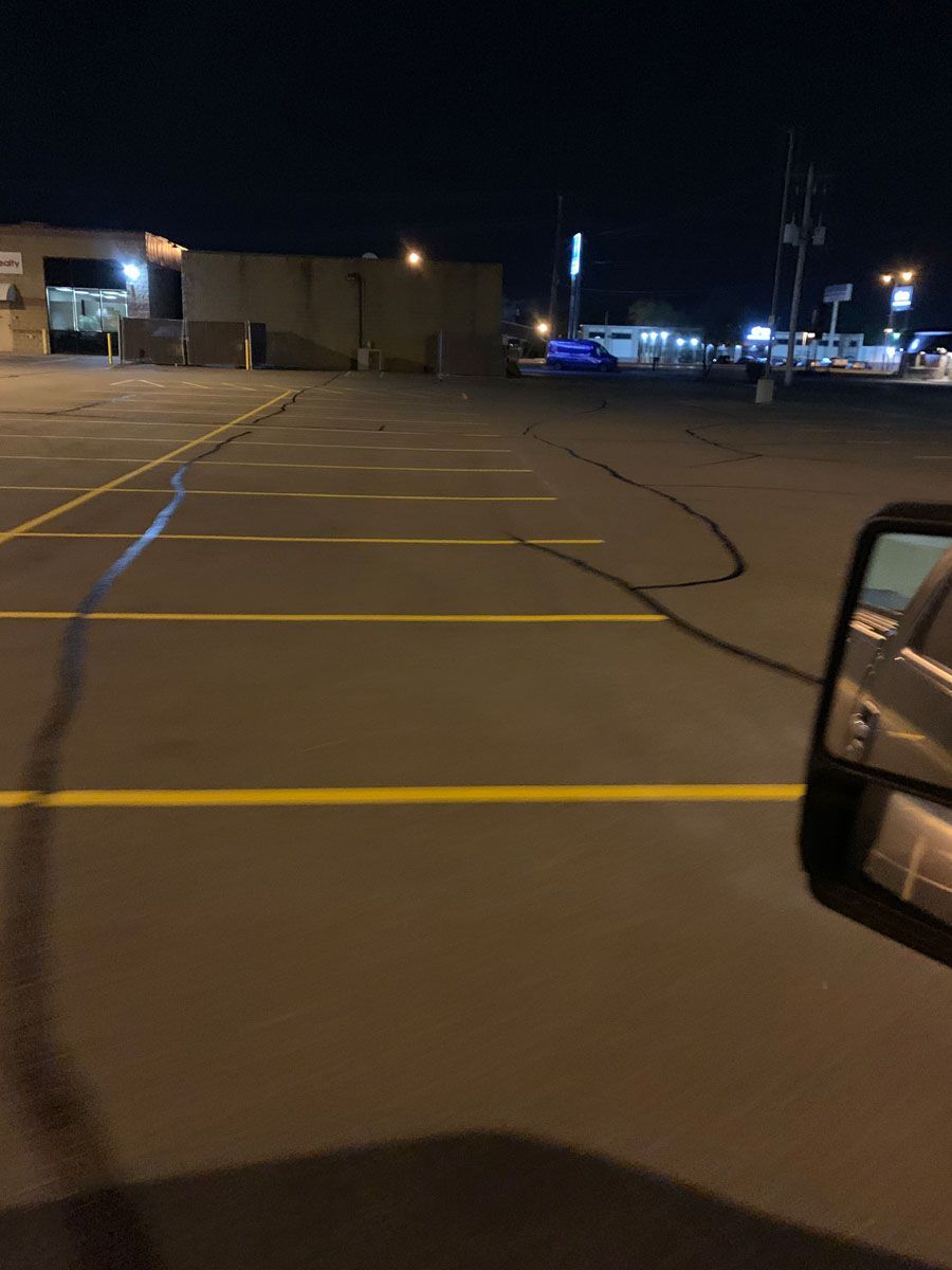 A car is parked in a parking lot at night.
