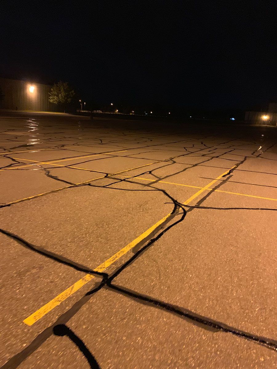 A parking lot at night with a lot of cracks in it