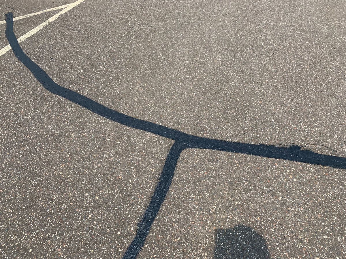 A person 's shadow is cast on the asphalt of a basketball court.