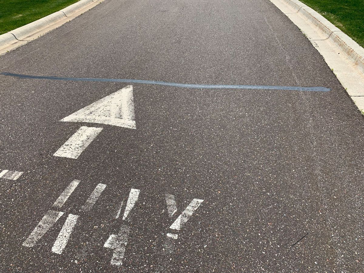 A white arrow is painted on the side of a road.