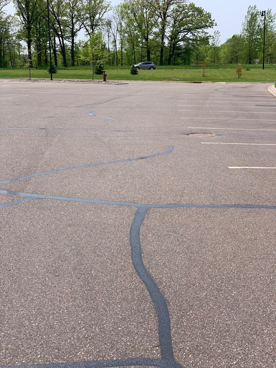 A car is parked in a parking lot with trees in the background