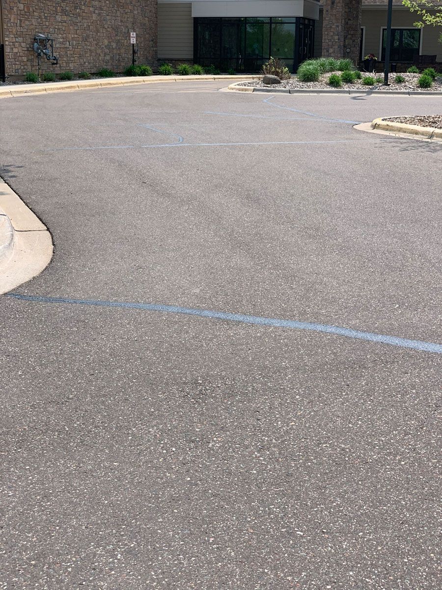 A parking lot with a building in the background and a blue line on the side of the road.