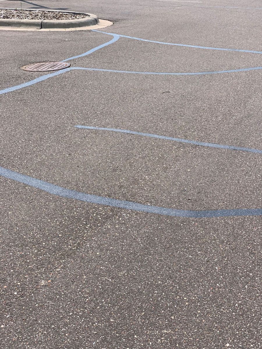 A close up of a parking lot with blue lines on it.