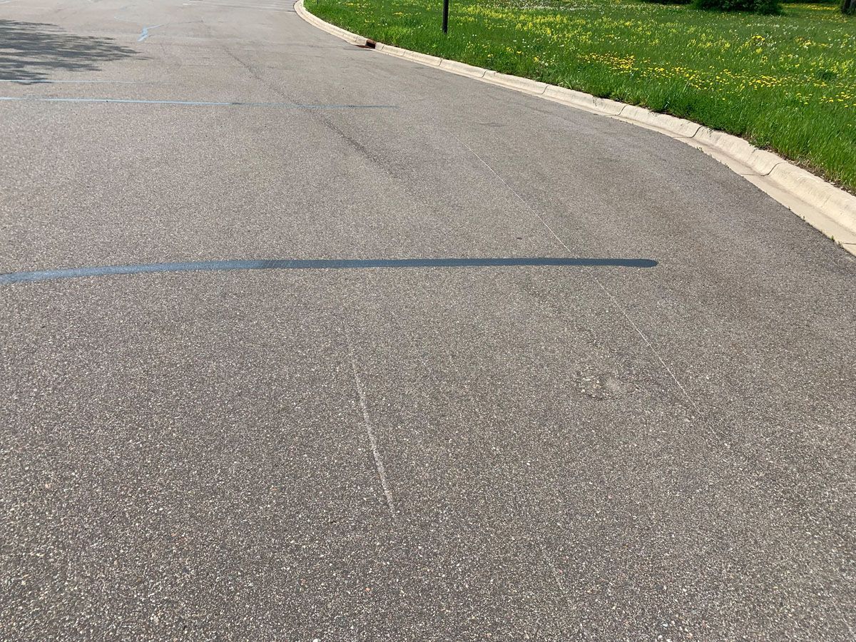 A shadow of a person is cast on the asphalt of a road.