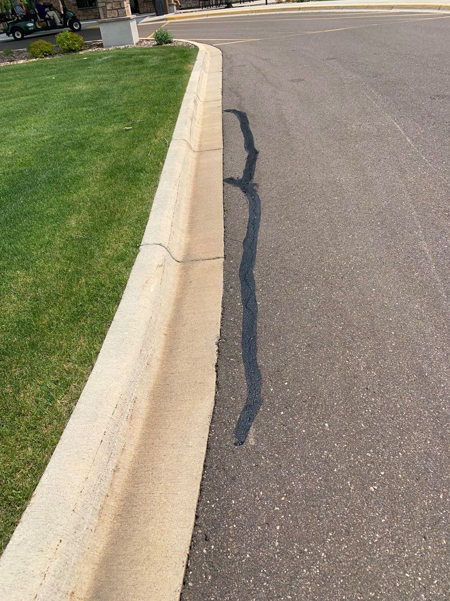 A curb on the side of a road with a shadow on the road.