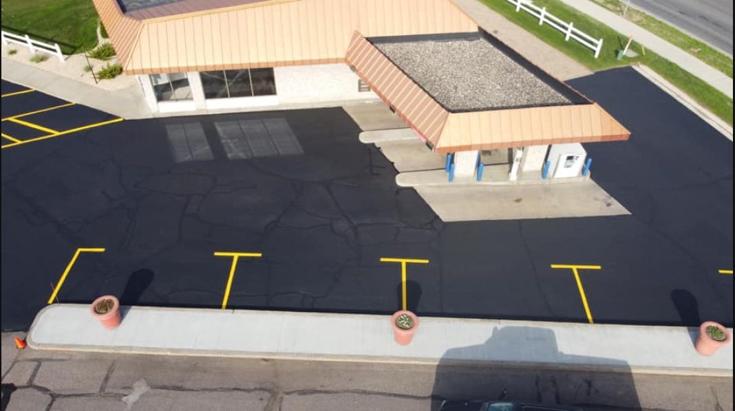 An aerial view of a parking lot with a building in the background.