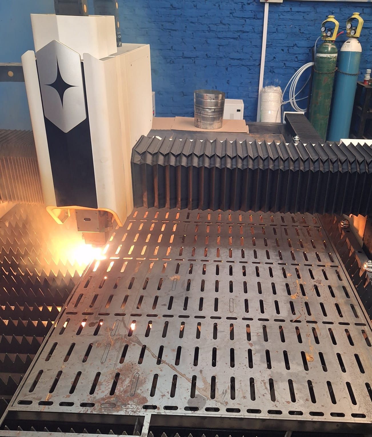 Cortadora láser cortando chapa metálica con chispas en una fábrica.