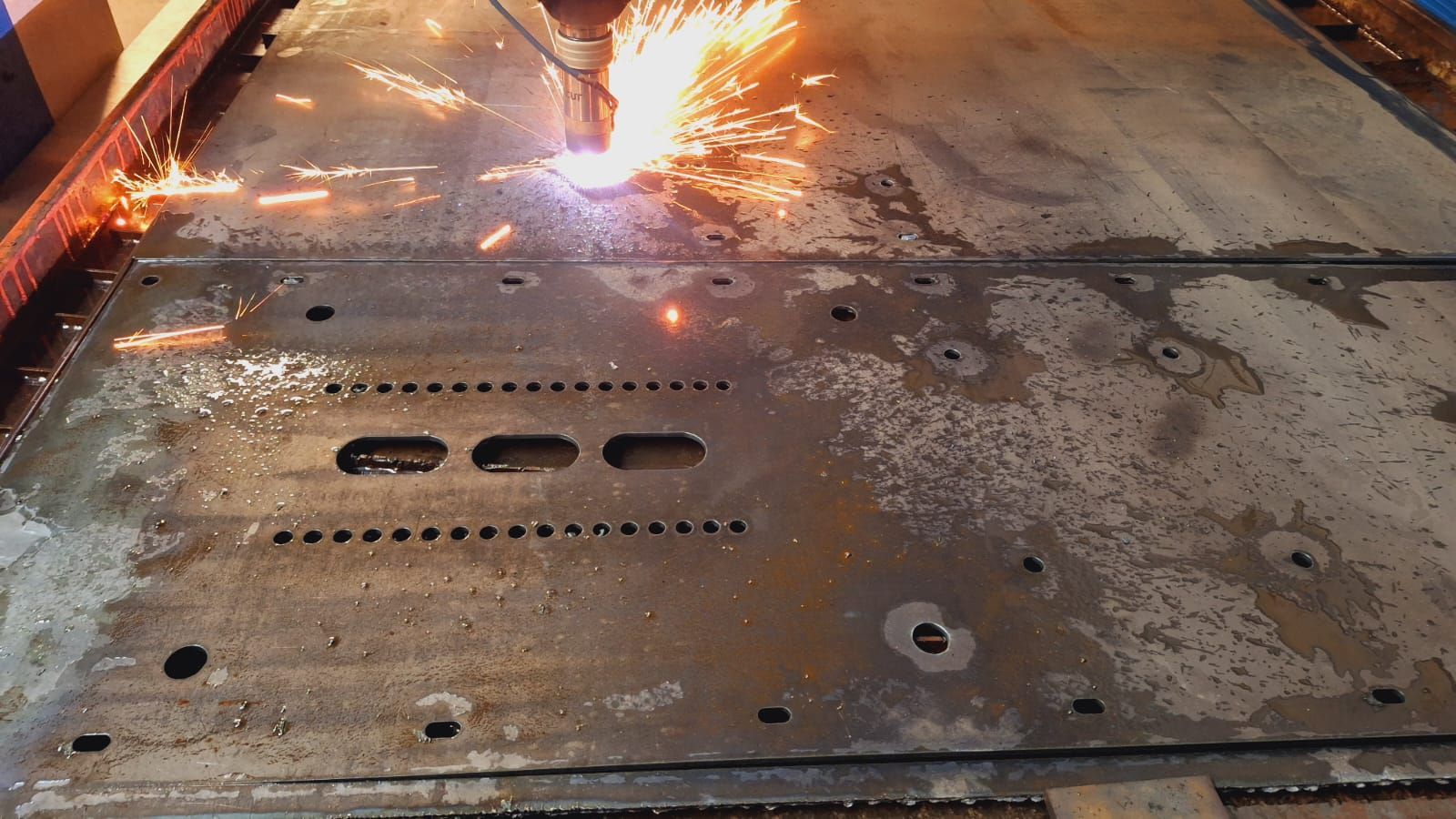 Cortador de plasma que corta metal, produciendo chispas brillantes.