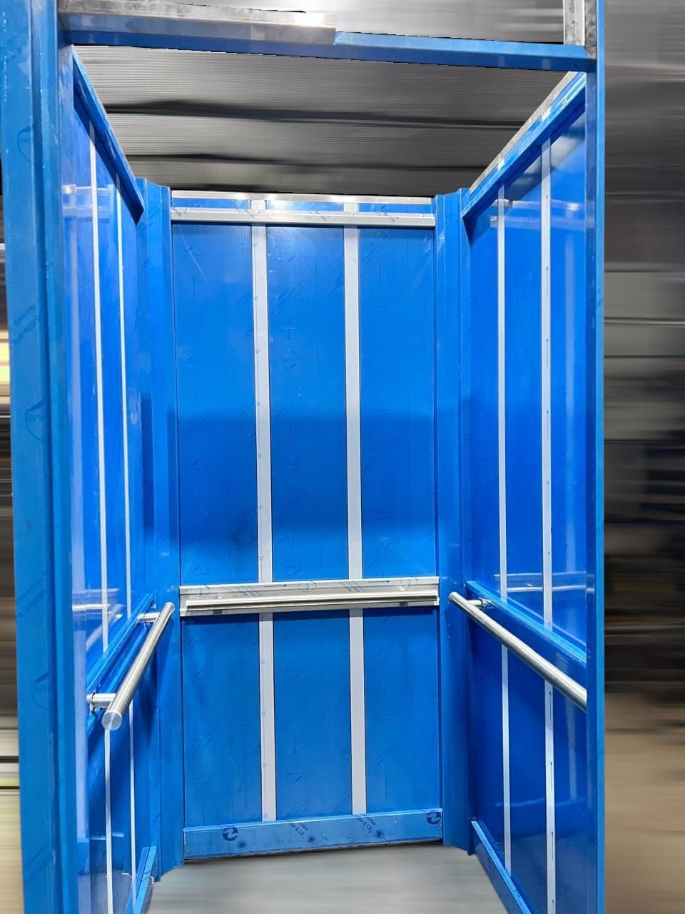 Conducto para ganado de metal azul con barras blancas verticales, visto desde el interior.