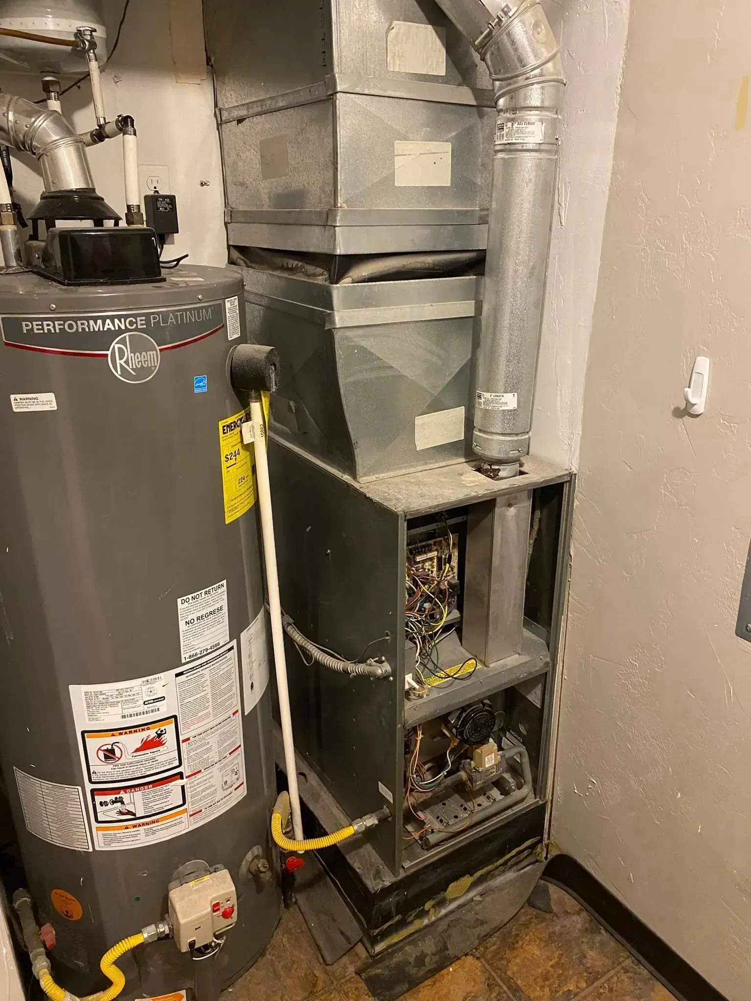 Water heater and furnace in a utility room with ductwork.