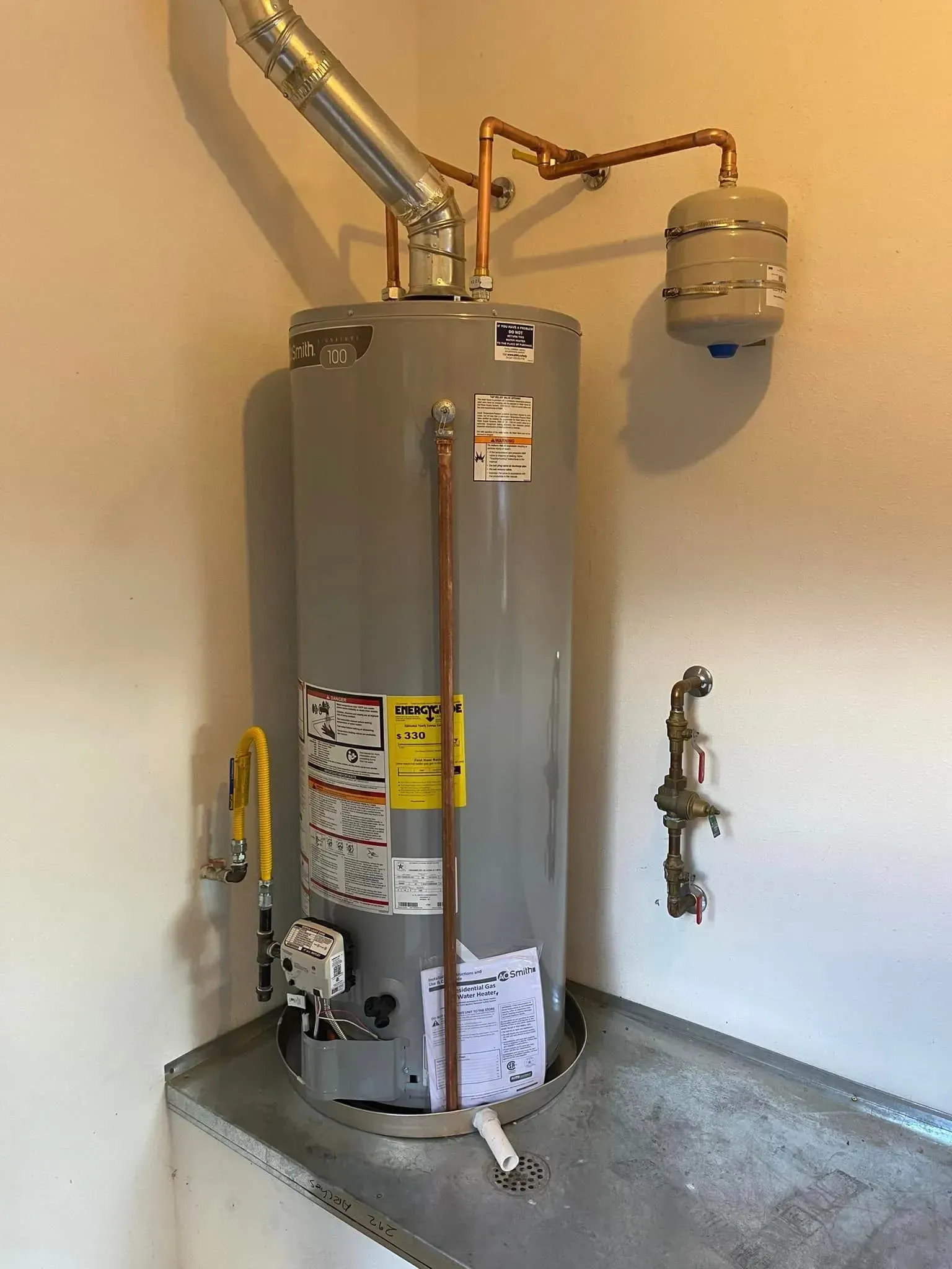 Water heater against a wall, with copper pipes and a vent.