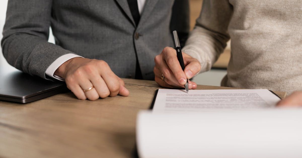 A man and a woman are signing a document at a table.