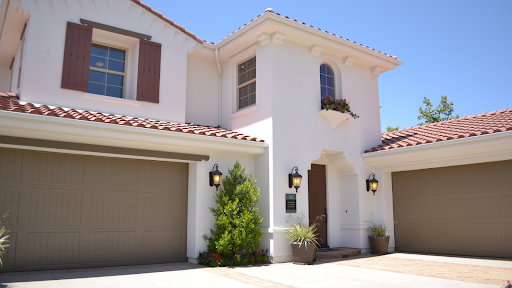 A white house with three garage doors and a red tile roof