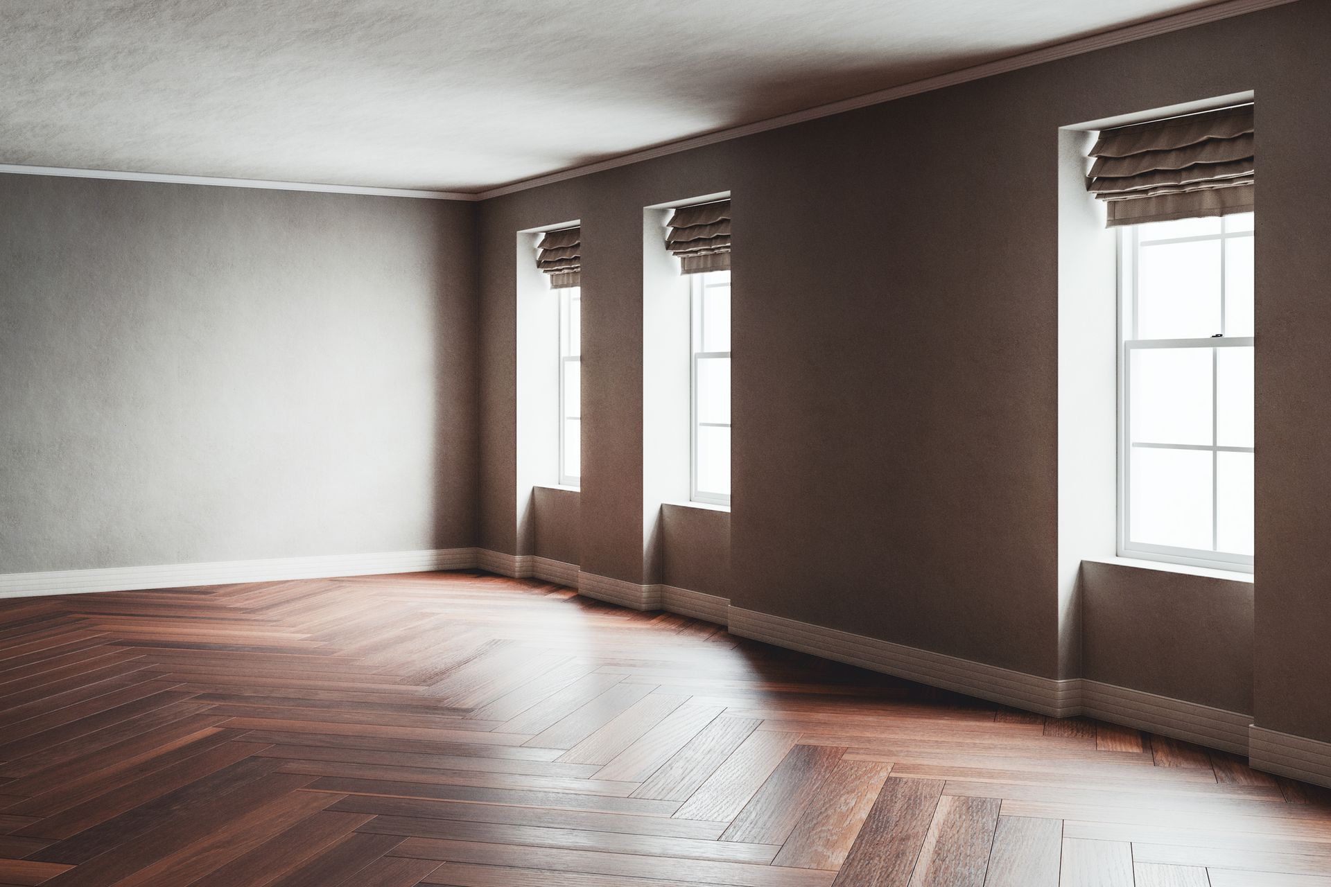 An empty room with a wooden floor and three windows.