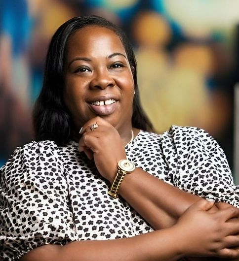 A woman wearing a leopard print shirt and a watch is smiling.