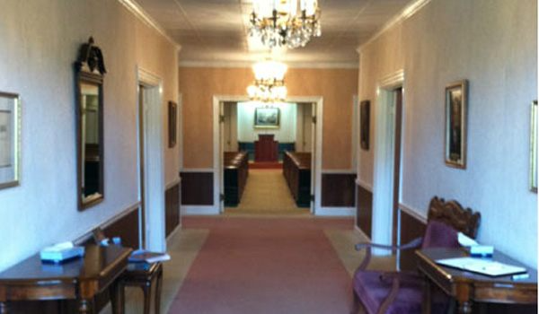 A hallway leading to a church with a chandelier hanging from the ceiling