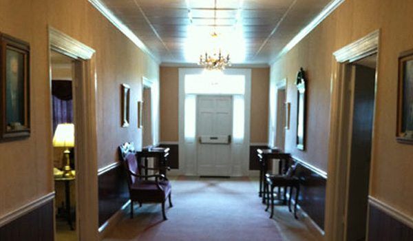 A long hallway with chairs and a chandelier hanging from the ceiling