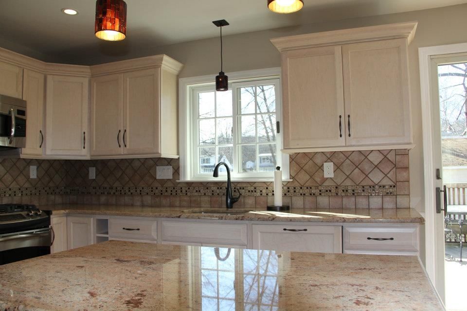 Cream-colored kitchen with granite countertops, tile backsplash, and window overlooking a deck.